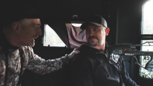Kip Adams and Keith Doyle in a hunting blind looking at each other with pride and excitement after Doyle shoots a deer.